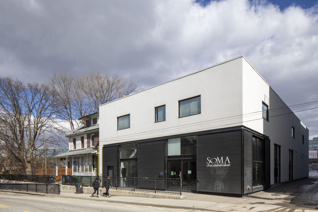 Soma Chocolatier's Brock Street location pictured is a two story building with black wooden cladding on the outside.